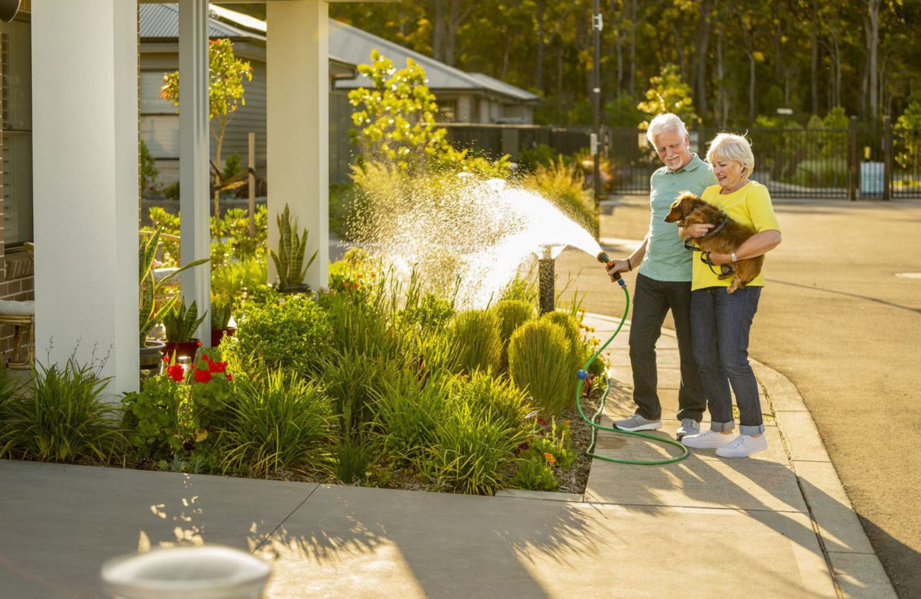 Man and woman outside their retirement village home with their dog at Blueheath at the Bower Medowie